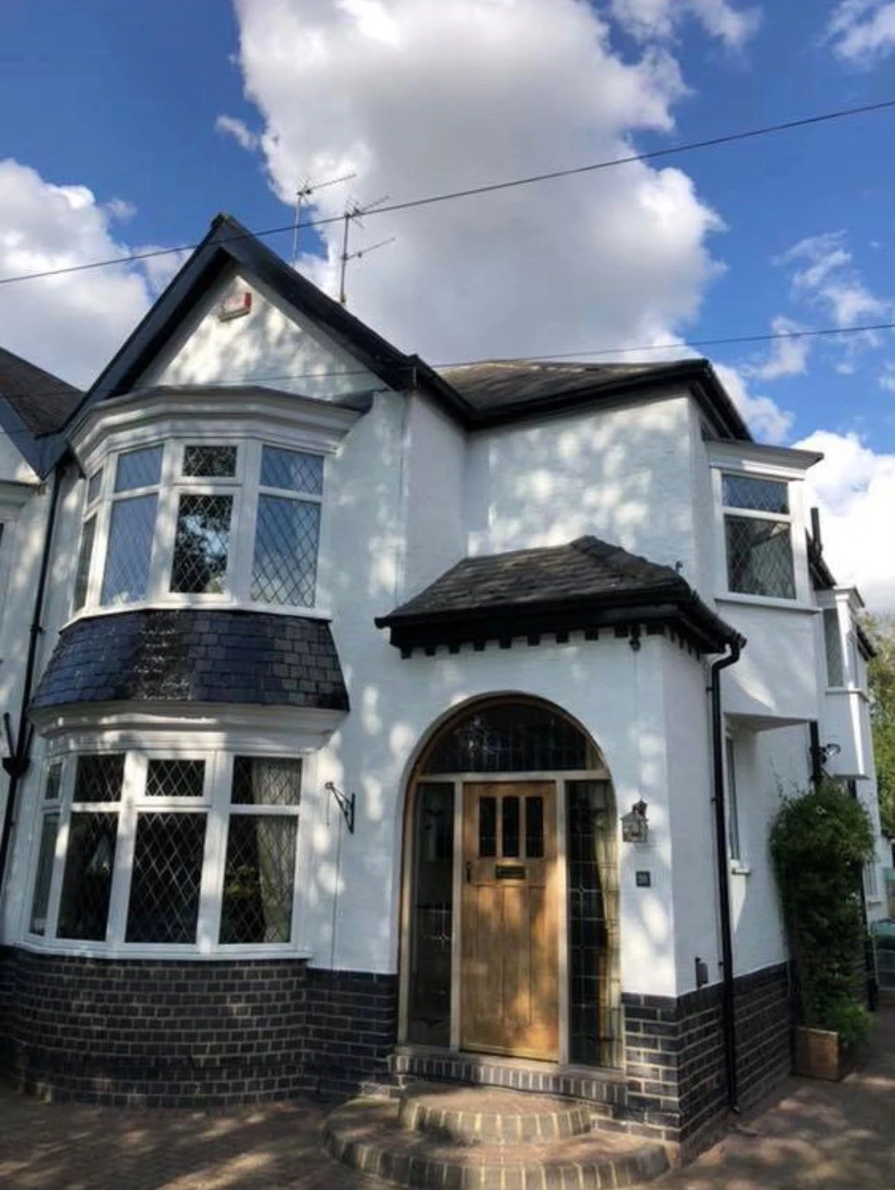 White exterior house painting on a bay-fronted home with fresh black masonry plinth