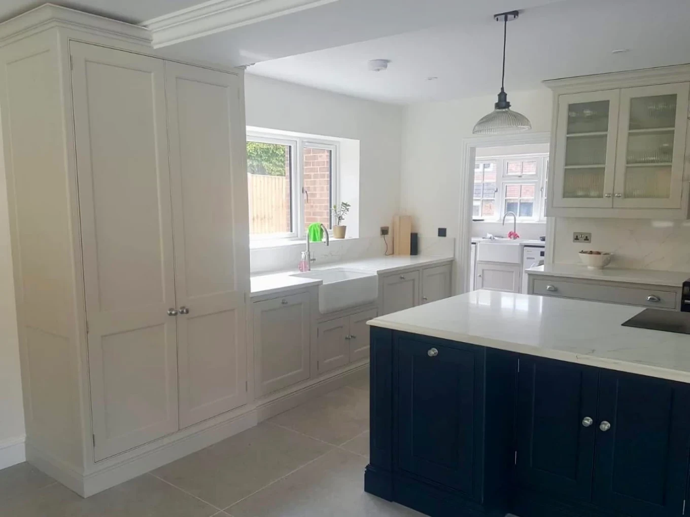 Two-tone painted kitchen with navy island and cream tall units