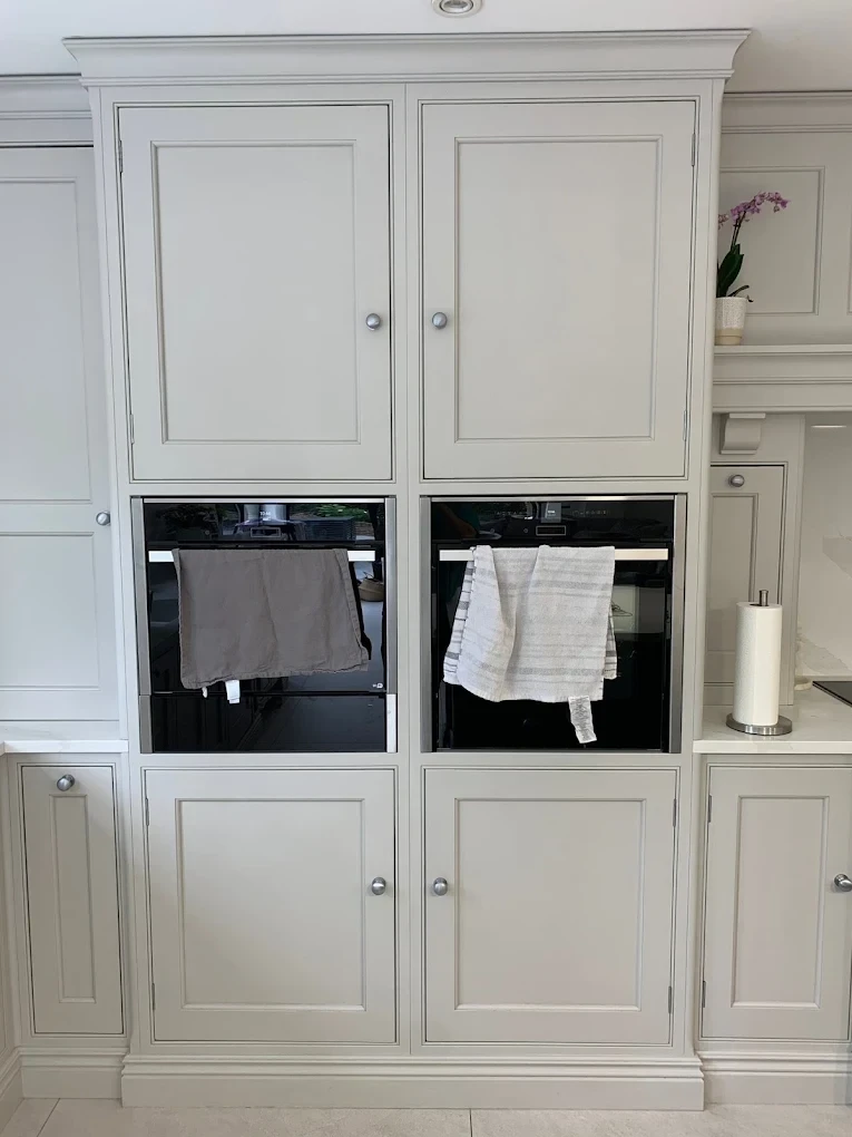 Painted bank of tall kitchen units housing double ovens