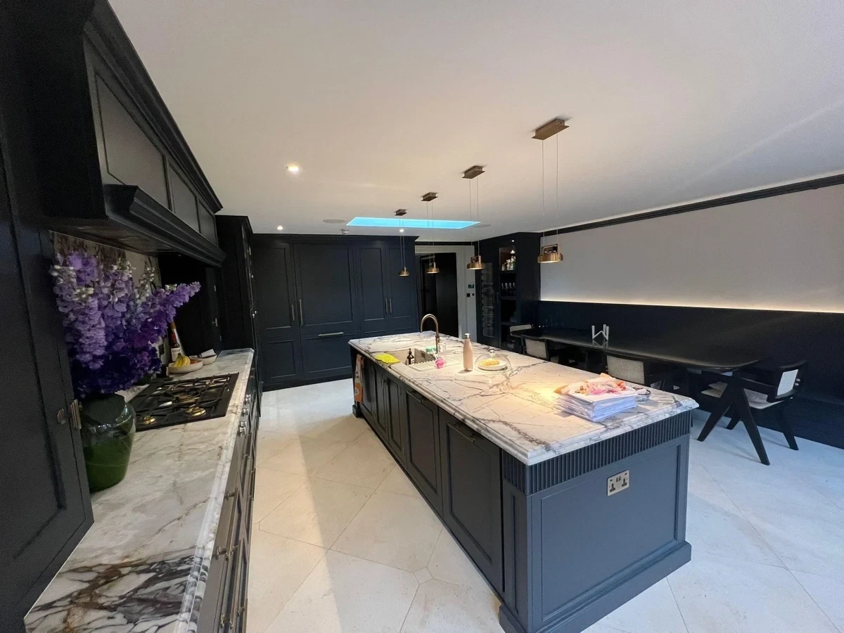 Dark painted kitchen island with marble worktop and wall units