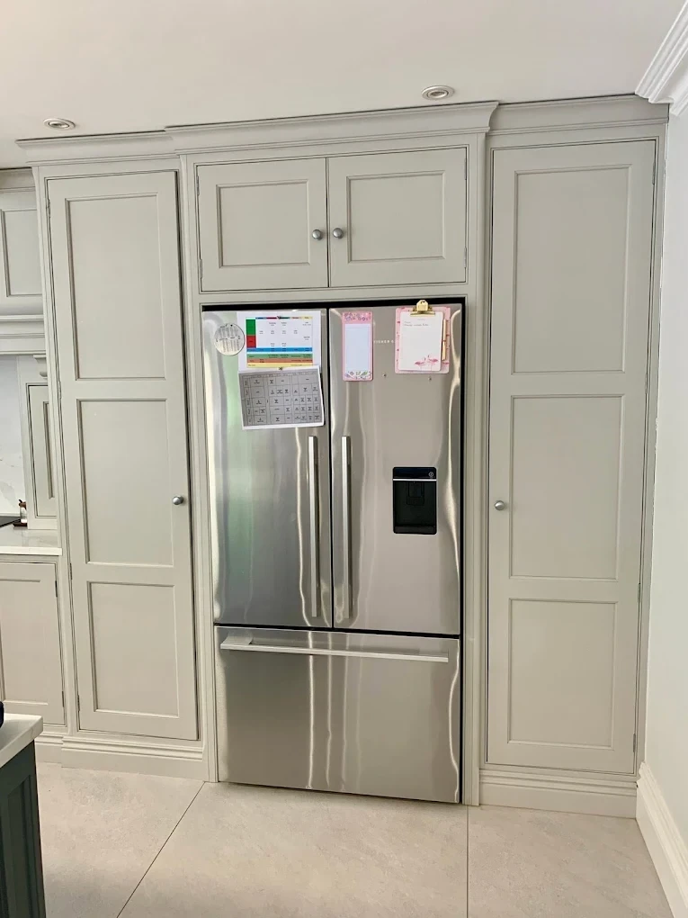 Tall painted kitchen cabinets framing an American-style fridge freezer