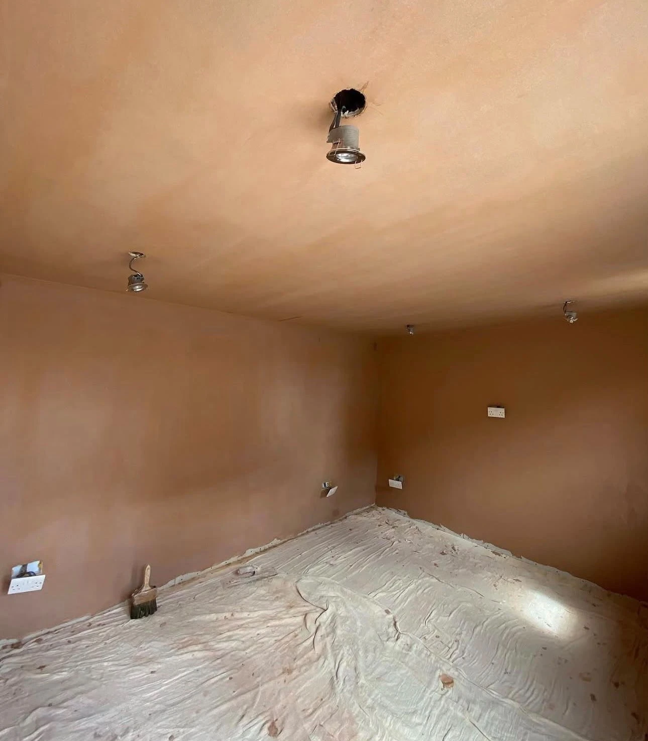Freshly skimmed walls and ceiling drying to a smooth pink plaster finish