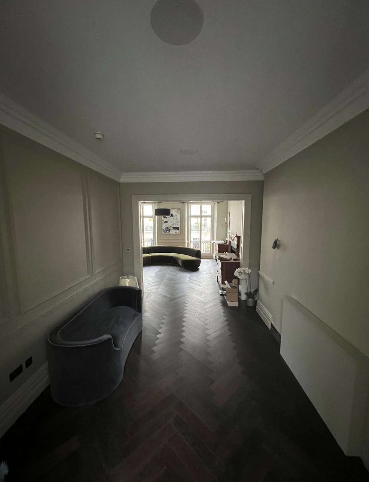 Panelled hallway painted in warm grey with dark herringbone floor