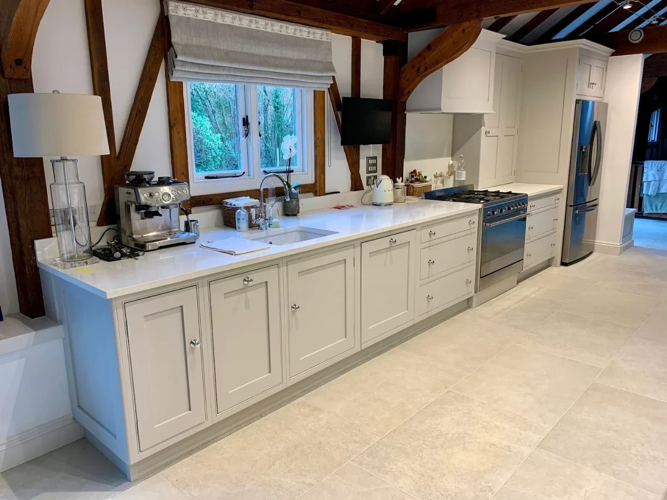 Painted kitchen in a beamed room with soft grey base units