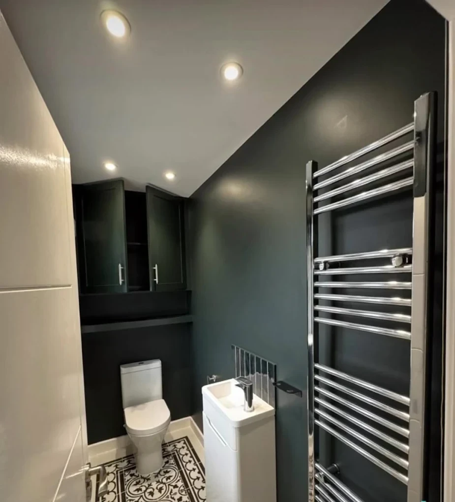 Bathroom painted in charcoal with chrome towel rail and white sanitaryware