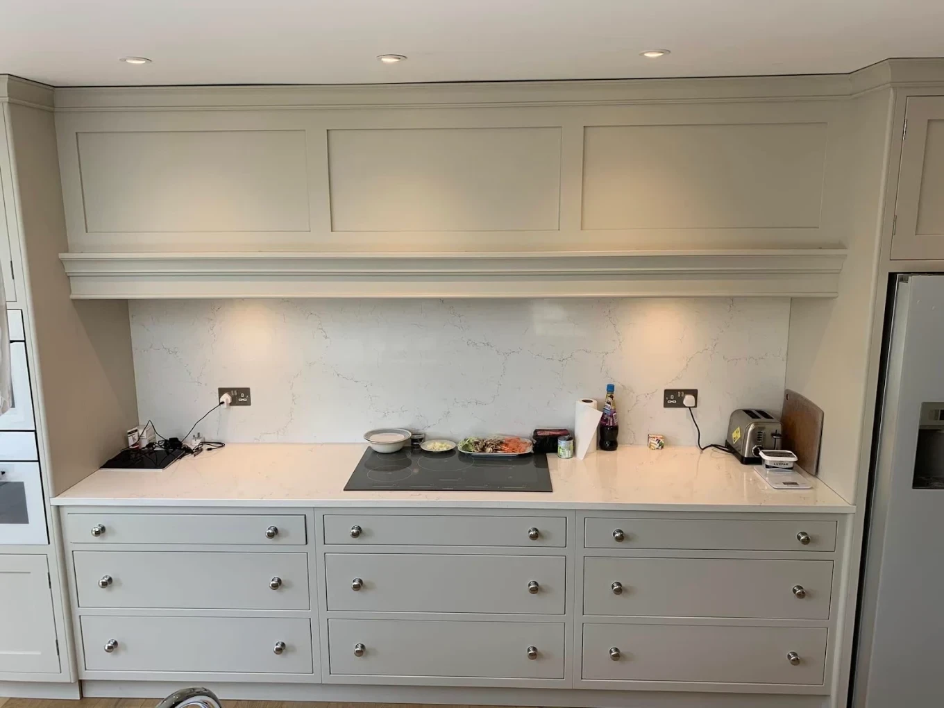 Painted kitchen hob wall with panelled hood and drawer units