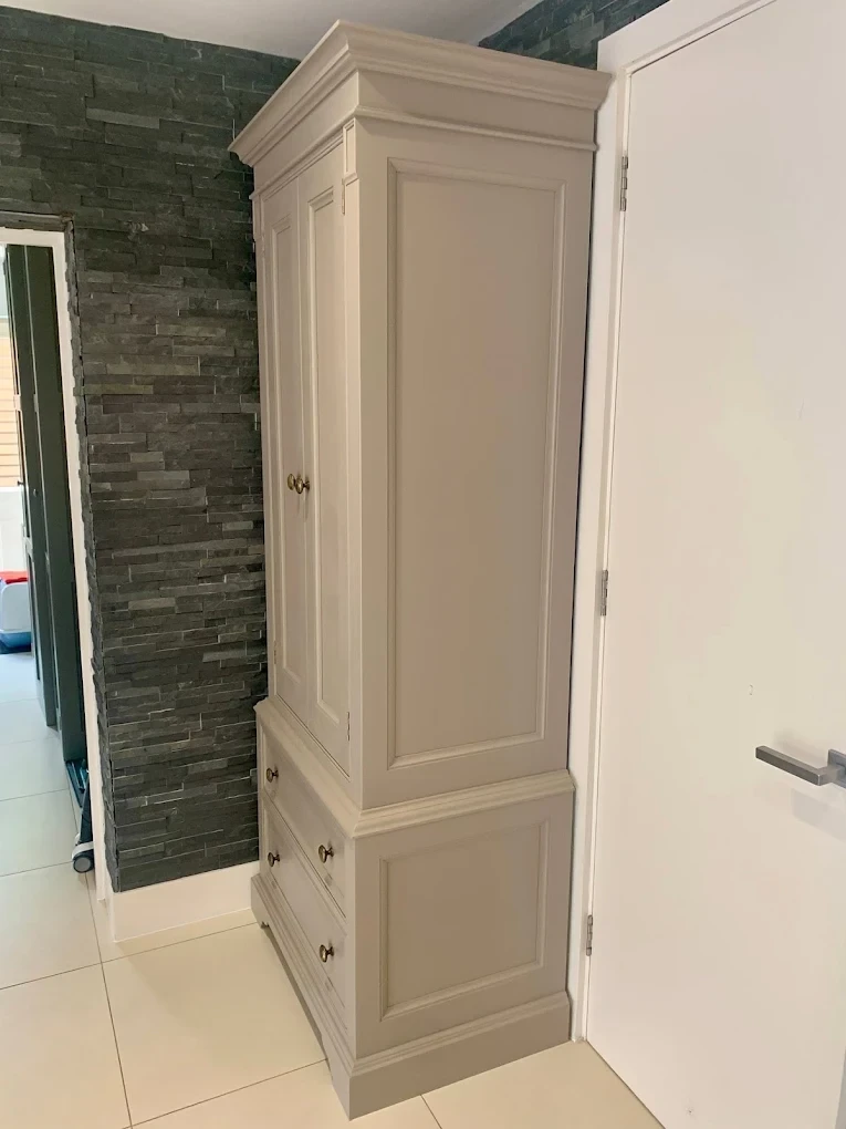 Tall painted joinery cabinet beside a slate feature wall