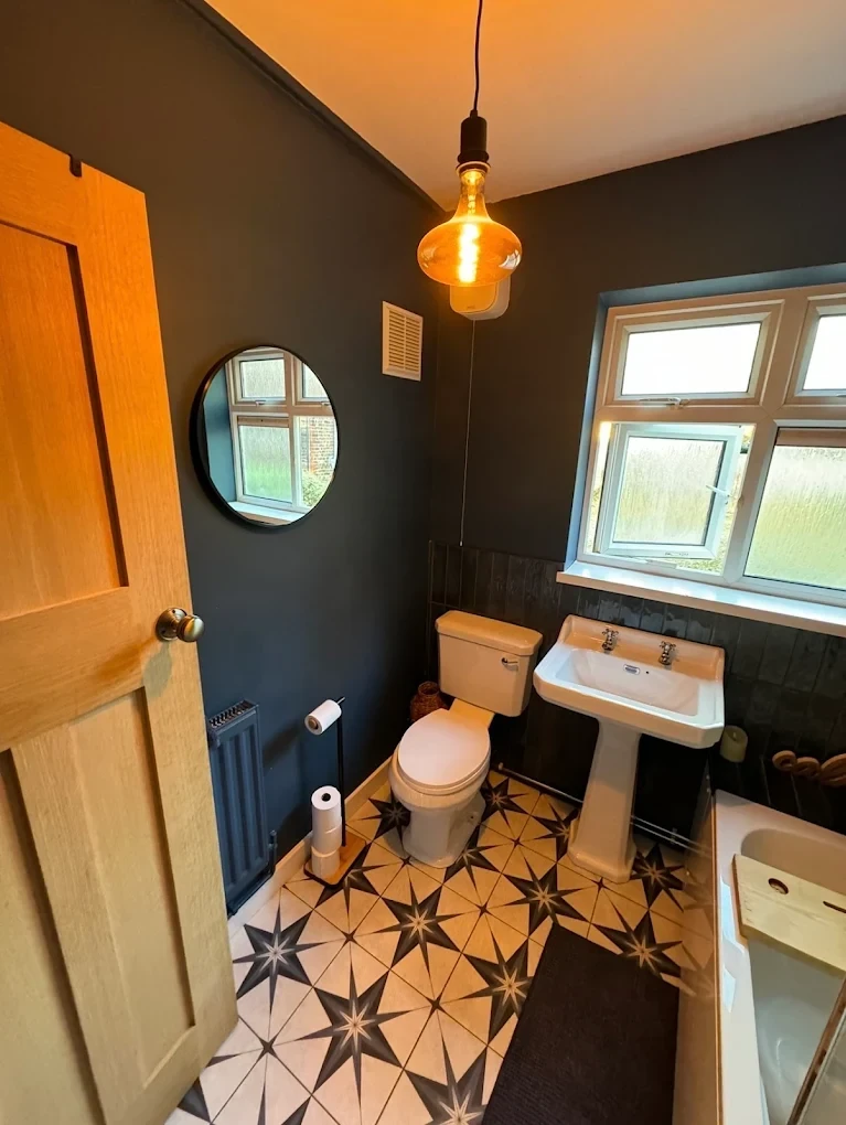 Cloakroom painted in dark green with oak door and patterned floor tiles