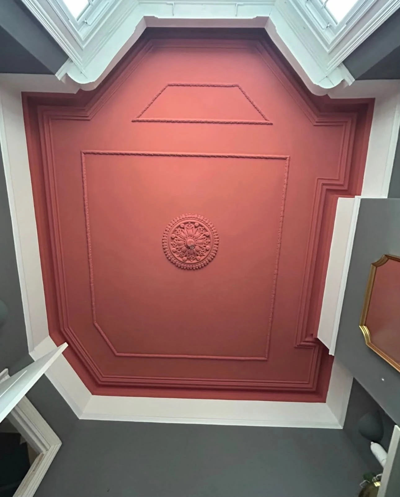 Ceiling panel painted in terracotta red with decorative mouldings and ceiling rose